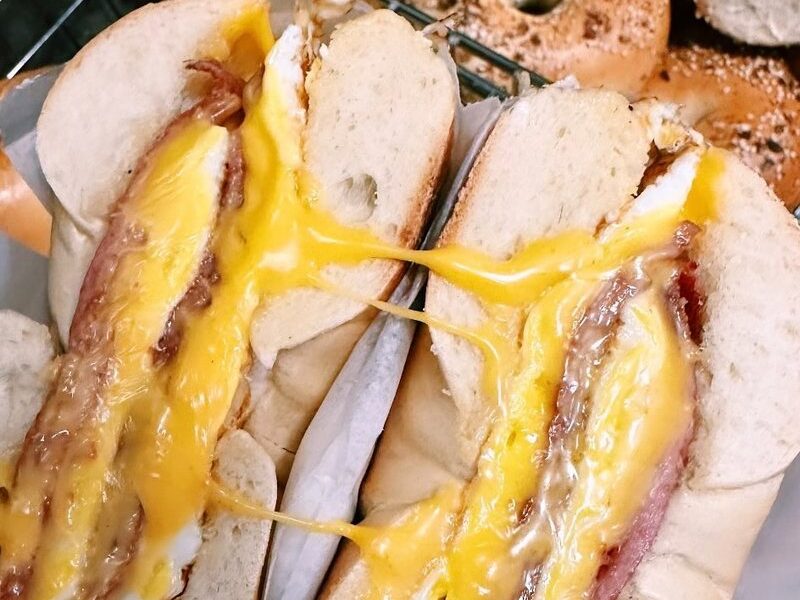 Taylor ham, egg and cheese on a bagel, cut in half with melted cheese