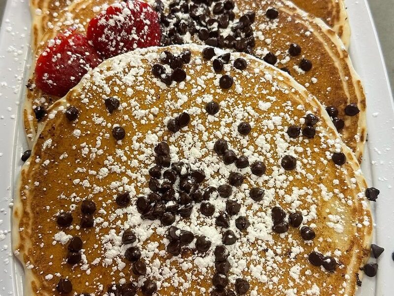 Chocolate chip pancakes dusted with powdered sugar and topped with strawberries
