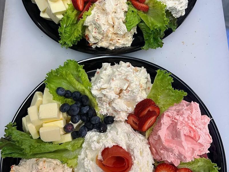 Catering trays of cream cheese spreads and butter with strawberries and blueberries on lettuce
